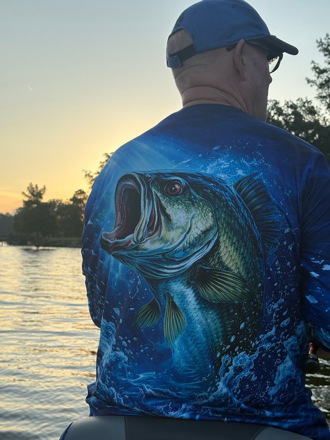 Customer wearing Midnight Bass Surge shirt on a boat at sunset